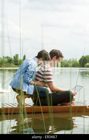 Couple using laptop computer on dock Stock Photo