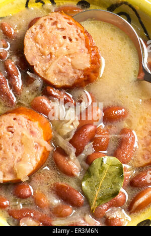 Polish sauerkraut, kielbasa, and bean soup with bay leaf garnish Stock Photo