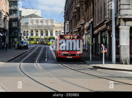 A Nottingham NET tram behind a red 'Trent' bus, on Market Street, in Nottingham, England. Stock Photo