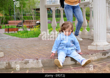 Naughty Girl 2 years old sitting on the ground Stock Photo