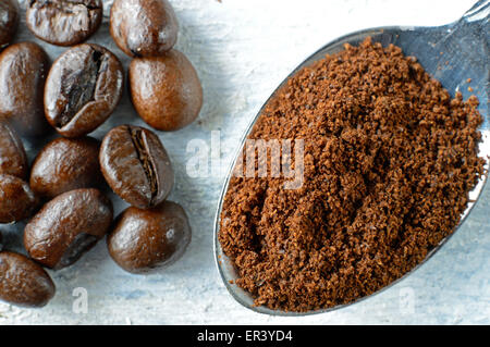 Ground coffee in a spoon and coffee beans on a white wooden background Stock Photo