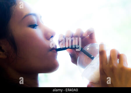 woman drinking iced coffee from a plastic cup with a straw Stock Photo