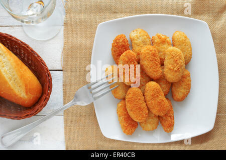 chicken nuggets served in a white bowl on a white wooden table of a rustic kitchen Stock Photo