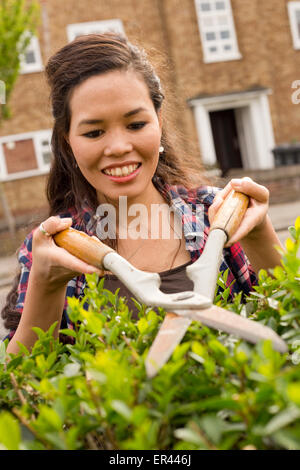 young woman cutting her hedge Stock Photo