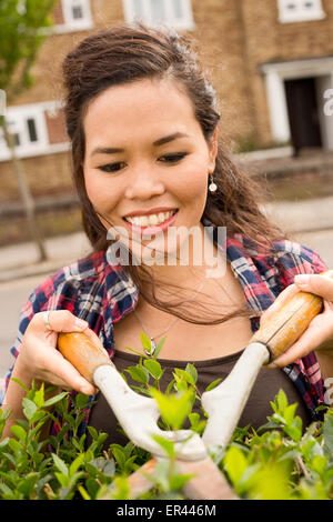 young woman cutting her hedge Stock Photo