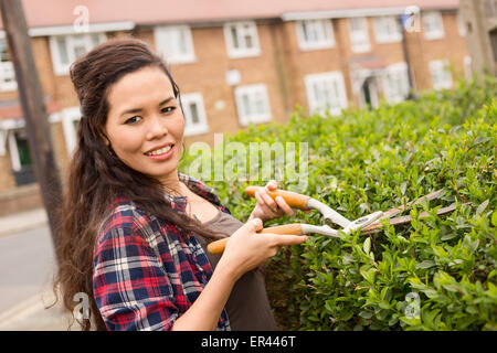 young woman cutting her hedge Stock Photo