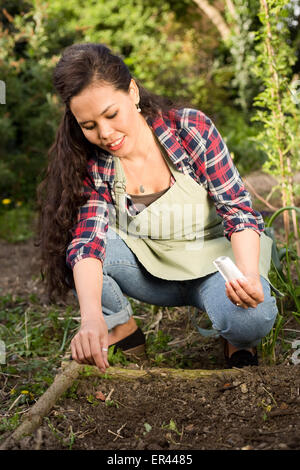young woman sowing seeds in the garden Stock Photo