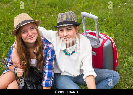 Two young girls girlfriends travellers, sitting on the grass. Stock Photo