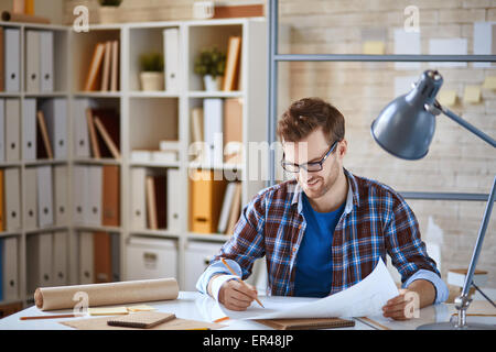 Young architect making corrections in blueprint Stock Photo