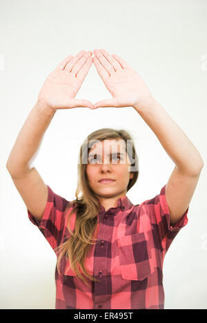 Young teenage girl is showing the Illuminati triangle symbol. White background behind her. Stock Photo