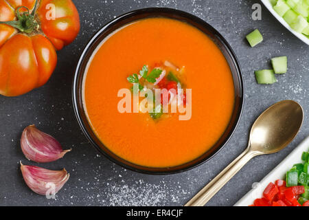 Spanish gazpacho, golden spoon, tomato, peppers, garlic and cucumber on a slate plate Stock Photo