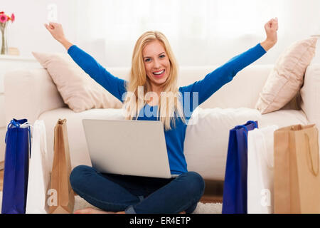 Excited young woman with online shopping Stock Photo