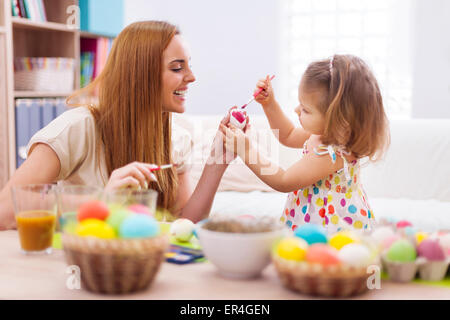 Happy mother helping baby painting on easter eggs. Debica, Poland Stock Photo
