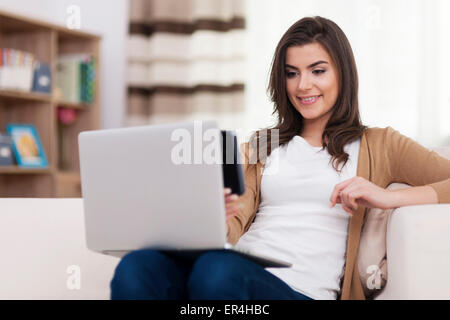 Beautiful woman sitting on a couch with a laptop Stock Photo