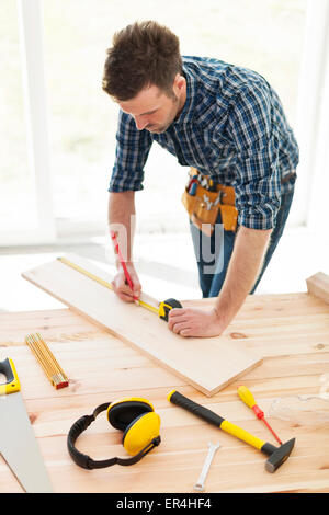 Carpenter checking dimensions of wooden plank. Pilzno, Poland Stock Photo