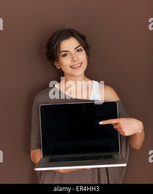 Beautiful woman pointing to caption space on laptop Stock Photo
