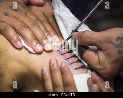 Bangkok, Bangkok, Thailand. 25th May, 2015. PAT, a Thai woman getting a tattoo, gets a tattoo from AJARN NENG ONNUT in his Sak Yant tattoo parlor. Sak Yant (Thai for ''tattoos of mystical drawings'' sak=tattoo, yantra=mystical drawing) tattoos are popular throughout Thailand, Cambodia, Laos and Myanmar. The tattoos are believed to impart magical powers to the people who have them. People get the tattoos to address specific needs. For example, a business person would get a tattoo to make his business successful, and a soldier would get a tattoo to help him in battle. The tattoos are blessed by Stock Photo