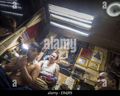 Bangkok, Thailand. 27th May, 2015. AJARN NENG ONNUT, blesses the tattoos of a Thai man who came to Ajarn Neng's home. Ajarn Neng is a revered master of sacred tattoos and sees people all day at his Bangkok home. Sak Yant (Thai for ''tattoos of mystical drawings'' sak=tattoo, yantra=mystical drawing) tattoos are popular throughout Thailand, Cambodia, Laos and Myanmar. The tattoos are believed to impart magical powers to the people who have them. People get the tattoos to address specific needs. Credit:  ZUMA Press, Inc./Alamy Live News Stock Photo
