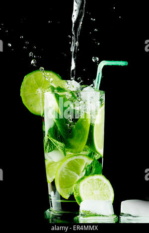 Pouring fresh mojito cocktail in glasses isolated on black background ...