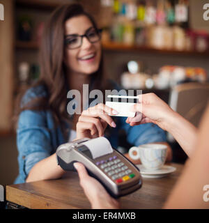 Happy woman paying for cafe by credit card. Krakow, Poland Stock Photo