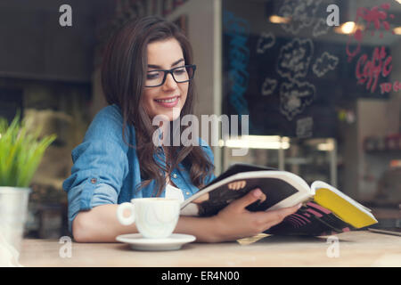 Smiling woman reading newspaper at cafe. Krakow, Poland Stock Photo
