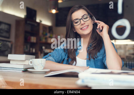 Smiling young woman talking on phone in cafe. Krakow, Poland Stock Photo