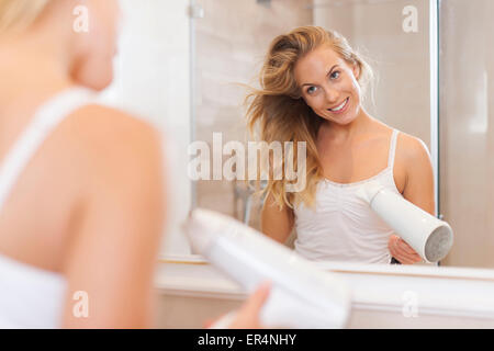 Smiling blonde woman drying hair in morning. Debica, Poland Stock Photo