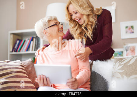 Sweet blonde girl showing something funny on digital tablet. Debica, Poland Stock Photo