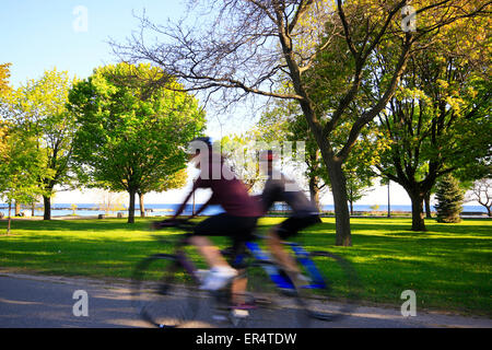 Motion blurred and unrecognizable female people cycling along waterfront trail near Humber Bay in Etobicoke, Toronto, Ontario, C Stock Photo