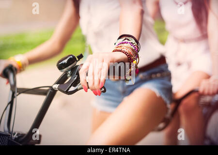 Close up of boho girls riding on bike. Krakow, Poland Stock Photo