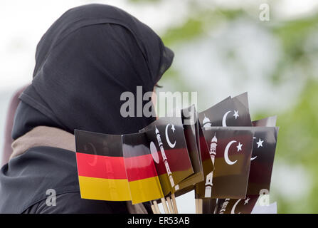 Hanau, Germany. 27th May, 2015. A veiled woman carries German flags and flags depicting the Islamic crescent during the opening of the new Bait-ul-Wahid mosque of the Ahmadiyya Muslim Jamad denomination in Hanau, Germany, 27 May 2015. The mosque has two 12-metres tall minarets and offers space for up to 500 people. Photo: BORIS ROESSLER/dpa/Alamy Live News Stock Photo