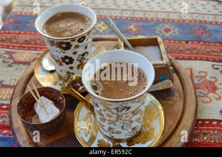 Two cups of Turkish coffee on wooden tray placed upon a colorful rug Stock Photo