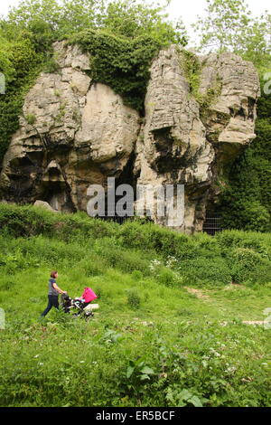 A visitor passes by caves at Creswell Crags, a limestone gorge on the border of Derbyshire and Nottinghamshire, Britain, UK Stock Photo