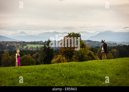 Couple wearing traditional Bavarian costumes standing on a meadow, Bad Toelz, Upper Bavaria, Germany Stock Photo