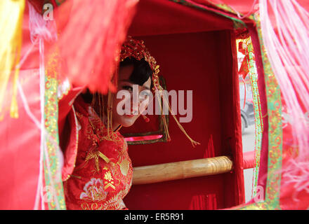 Pingdingshan, Henan, CHN. 27th May, 2015. Pingdingshan, CHINA - May 27 2015: (EDITORIAL USE ONLY. CHINA OUT) The bride in traditional wedding dress sits in the sedan chair. This is a traditional Chinese wedding ceremony, including the bride sitting in a sedan chair, the bridegroom riding a horse, the accompaniment of music, the groom lifting the veil on the bride, etc. It has no emissions, saves resources and money, and is also joyous and romantic. Credit:  SIPA Asia/ZUMA Wire/Alamy Live News Stock Photo