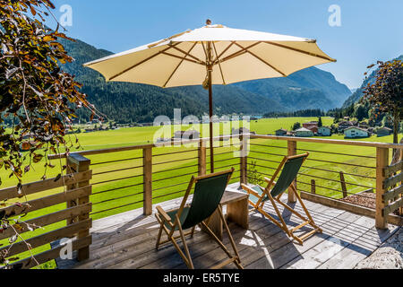 Deckchairs and sunshade on a terrace, lake Achensee and Achenkirch in background, Tyrol, Austria Stock Photo