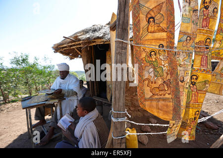 Priest and students beside a hut, goatskins with paintings of biblical scenes in Geez, Bet Giyorgis, Church of St. George, Lalib Stock Photo