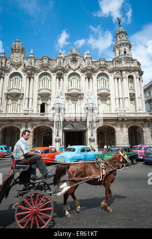 HAVANA, CUBA - JUNE, 2011: Traditional horse and buggy passes by row of brightly colored vintage American cars. Stock Photo