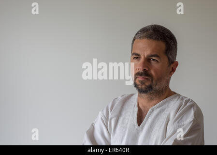 Portrait of thoughtful mature man with serious facial expression beard standing against the wall. Natural soft light and colors, Stock Photo
