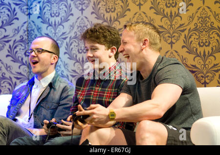 Three males having fun and laughing while playing computer games on a sofa. Stock Photo