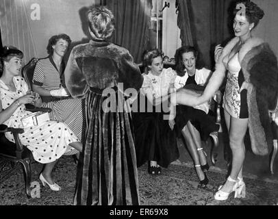 On the right mannequin Joan Sidsaph, 20, in a natural white and blue fox looks on as fashion experts study a full-length striped beaver-lamb evening coat in platinum and black (left). July 1948 P024379 Stock Photo