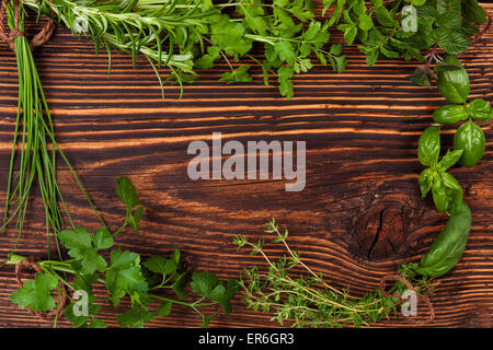 Culinary herbs background with copy space. Fresh basil, cilantro, chive, parsley and mint herbs on brown wooden background Stock Photo