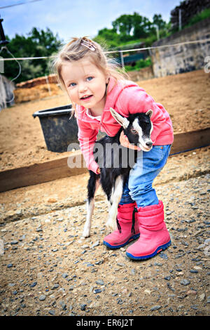 little girl with a goat kid in front of the farm Stock Photo