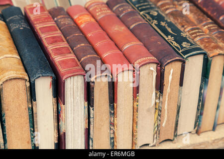 Old used vintage books with colorful leather covers lay on the shelf Stock Photo