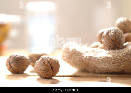 Some walnuts scattered on a sack on a rustic wooden kitchen. Stock Photo