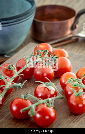 Some vine ripened tomatoes on chopping board. Stock Photo