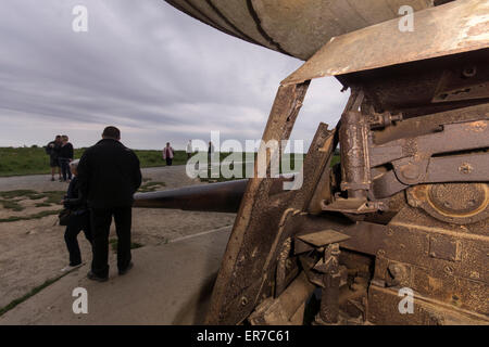 Lounges sur mer, Normandy, France. Tourists near an old, rusting German gun at dusk. Stock Photo