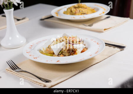 Prepared Dishes Served at Simple Place Settings on Restaurant Table Accented with White Flower Vase Stock Photo