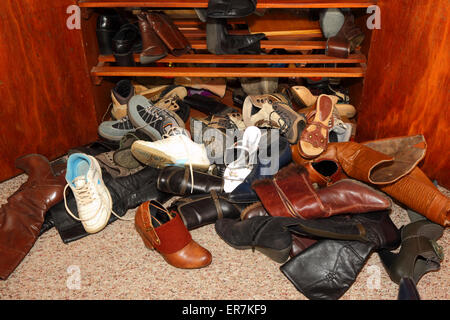 Selection of womens shoes scattered untidily on floor in front of wardrobe in bedroom Stock Photo
