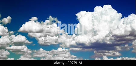 Puffy white cumulus clouds have been digitally enhanced to show against a sky of varied blue colors. Stock Photo